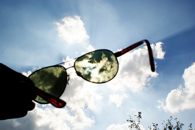 サングラスを持って空を見ている写真