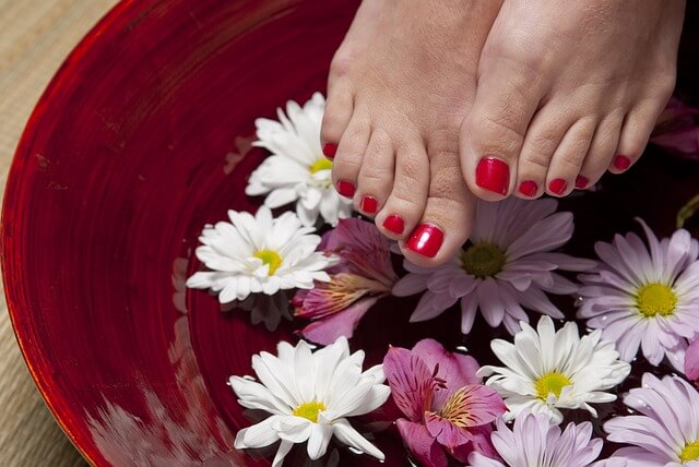 ペディキュアを塗った女性の足が花びらの上に見えている